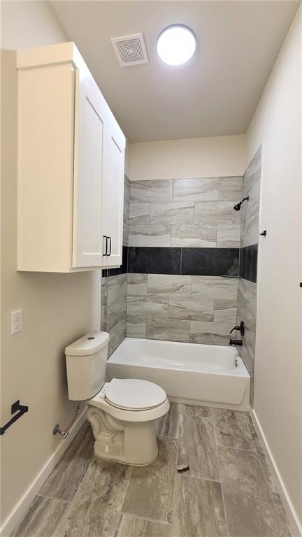 bathroom with toilet and tiled shower / bath