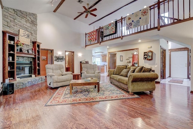 living room featuring ceiling fan, a fireplace, high vaulted ceiling, and wood-type flooring