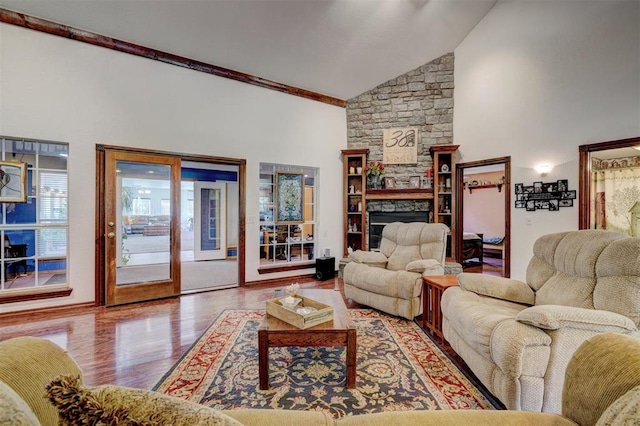 living room with a stone fireplace, high vaulted ceiling, and hardwood / wood-style flooring