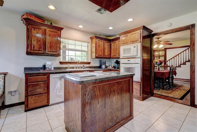 kitchen with white appliances, ceiling fan, sink, light tile patterned floors, and a center island