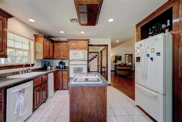 kitchen featuring light tile patterned flooring, white appliances, sink, a textured ceiling, and a kitchen island