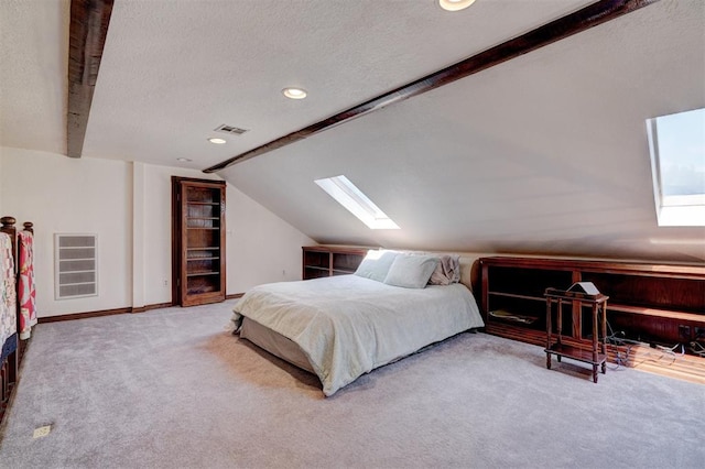 bedroom with lofted ceiling with skylight, carpet floors, and a textured ceiling