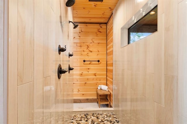 bathroom with a tile shower, wooden walls, and wood ceiling