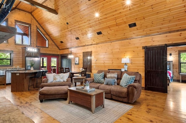 living room featuring wood walls, wooden ceiling, high vaulted ceiling, light hardwood / wood-style flooring, and a barn door