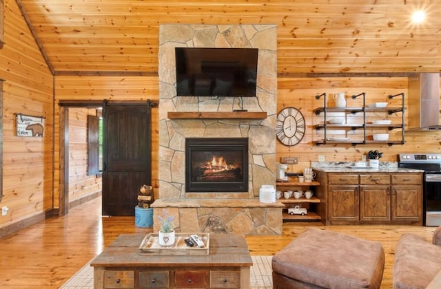 living room with vaulted ceiling, light hardwood / wood-style flooring, wooden ceiling, a stone fireplace, and wood walls