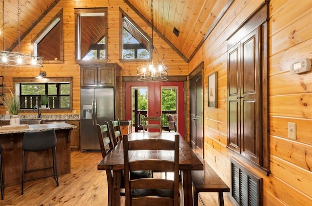 dining space with light wood-type flooring, wooden ceiling, and wooden walls