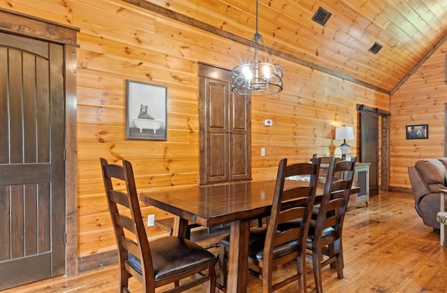 dining area featuring lofted ceiling, a barn door, wood-type flooring, and wooden ceiling