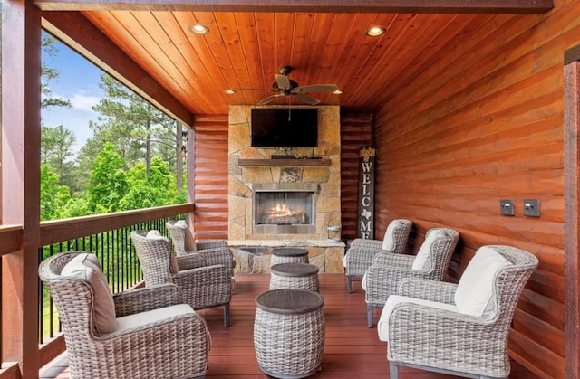 wooden deck with an outdoor stone fireplace and ceiling fan