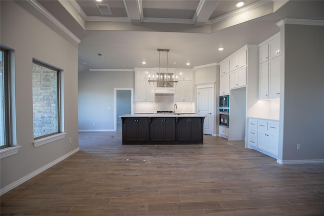 kitchen featuring dark hardwood / wood-style flooring, white cabinetry, a center island with sink, and pendant lighting