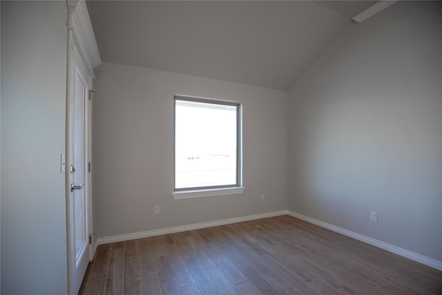 spare room featuring vaulted ceiling and hardwood / wood-style flooring