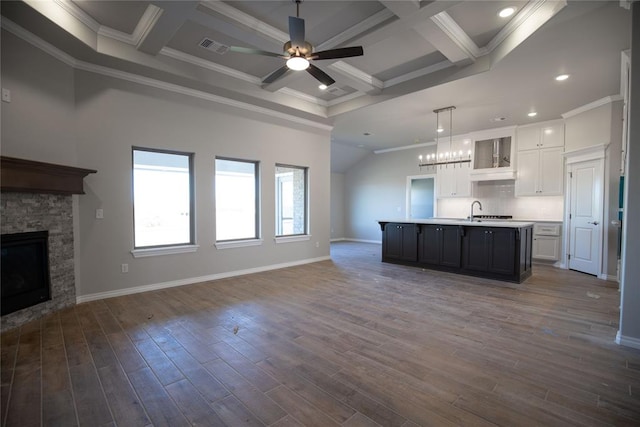 kitchen with white cabinets, dark hardwood / wood-style flooring, an island with sink, and ornamental molding