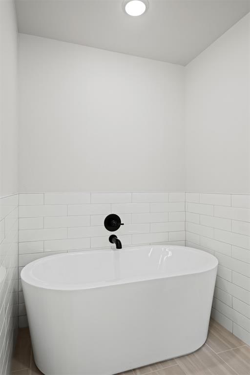 bathroom featuring a washtub and tile walls