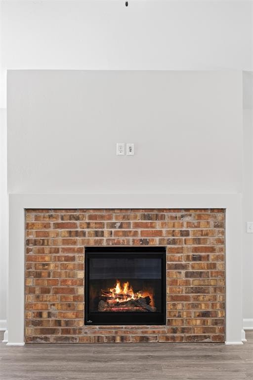 details featuring hardwood / wood-style flooring and a brick fireplace