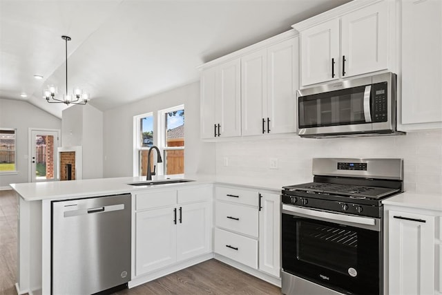 kitchen featuring kitchen peninsula, stainless steel appliances, vaulted ceiling, sink, and white cabinetry