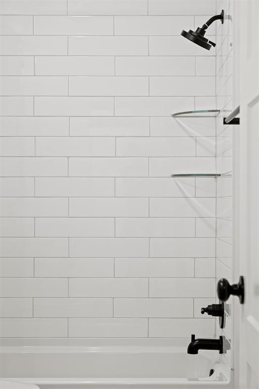 interior details featuring tiled shower / bath combo