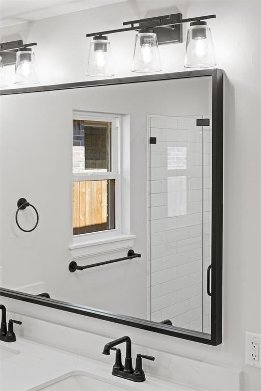 bathroom featuring a shower with shower door and sink