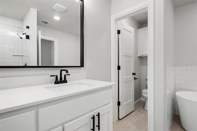 bathroom featuring vanity, a bathing tub, tile patterned floors, toilet, and tile walls