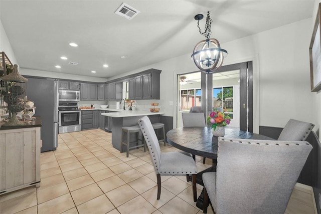 dining space featuring sink, light tile patterned floors, and ceiling fan with notable chandelier