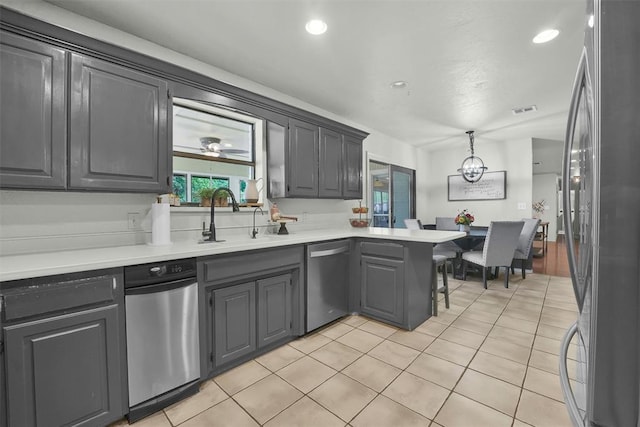 kitchen with sink, hanging light fixtures, light tile patterned floors, kitchen peninsula, and stainless steel appliances