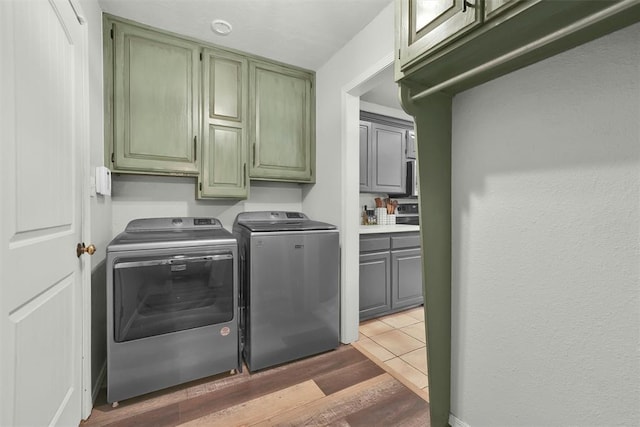 clothes washing area featuring hardwood / wood-style floors, cabinets, and independent washer and dryer