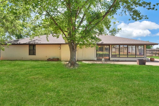 rear view of house with a sunroom and a lawn