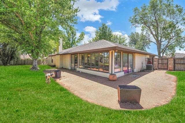 rear view of property with central air condition unit, a sunroom, a lawn, and a patio