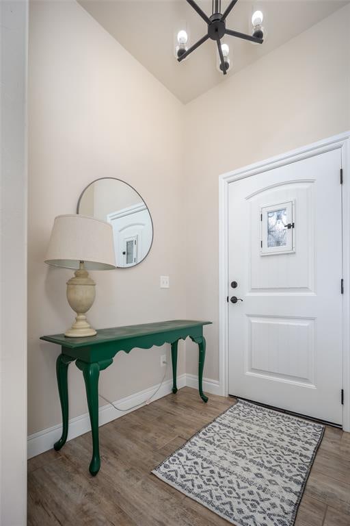 foyer featuring wood-type flooring, vaulted ceiling, and a notable chandelier