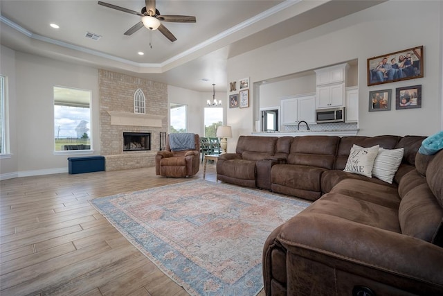 12561 Summit Ln, Blanchard, OK 73010 - living room featuring ceiling fan with notable chandelier, a healthy amount of sunlight, a raised ceiling, and light wood-type flooring