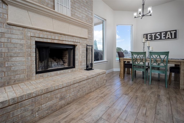 dining space featuring a fireplace, wood-type flooring, and an inviting chandelier