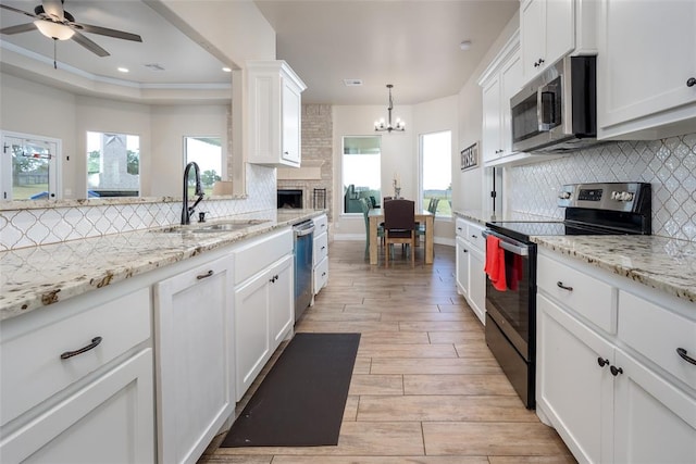 kitchen featuring sink, light hardwood / wood-style flooring, decorative backsplash, white cabinetry, and stainless steel appliances