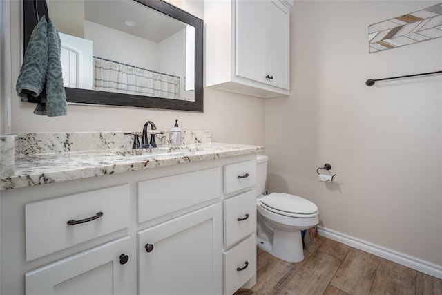 bathroom with hardwood / wood-style flooring, vanity, and toilet