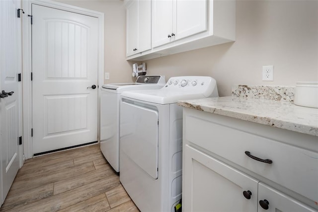 laundry area featuring cabinets, light wood-type flooring, and washing machine and clothes dryer