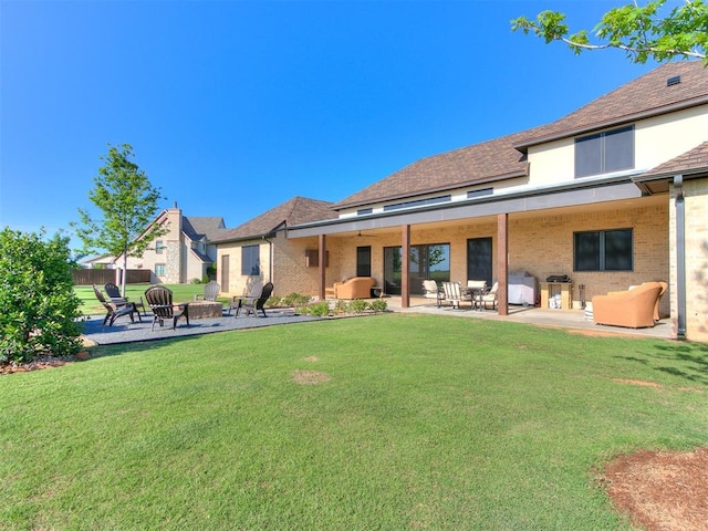 rear view of property with an outdoor fire pit, a patio area, and a lawn