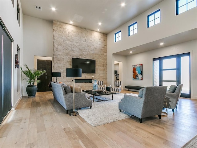 living room featuring a high ceiling, light wood-type flooring, and a healthy amount of sunlight