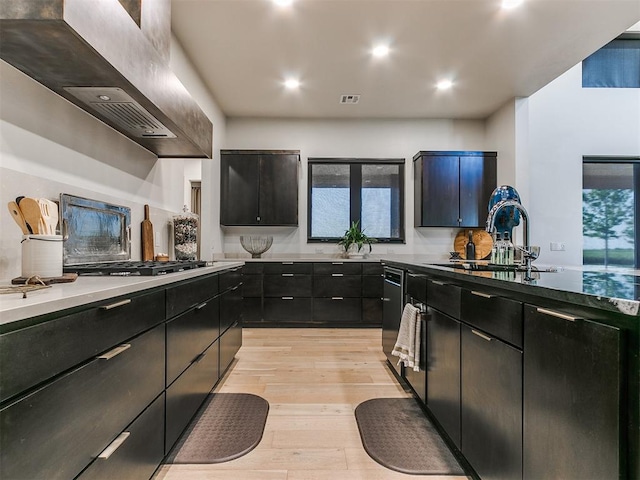 kitchen featuring wall chimney range hood, sink, decorative backsplash, light hardwood / wood-style floors, and stainless steel gas cooktop