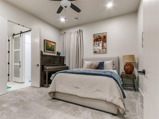 carpeted bedroom featuring ceiling fan and a barn door