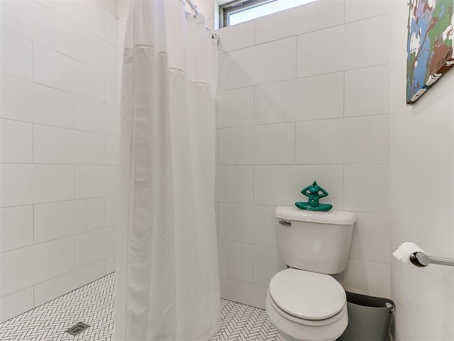 bathroom with tile patterned floors, toilet, tile walls, and walk in shower