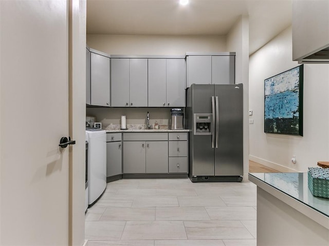 kitchen featuring separate washer and dryer, stainless steel fridge, gray cabinets, and sink