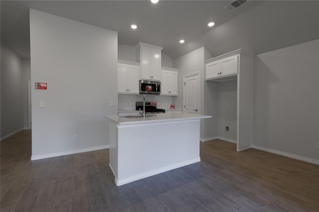 kitchen featuring decorative backsplash, appliances with stainless steel finishes, a kitchen island with sink, dark hardwood / wood-style floors, and white cabinetry