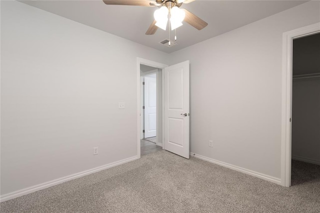 unfurnished bedroom with ceiling fan, a walk in closet, light carpet, and a closet