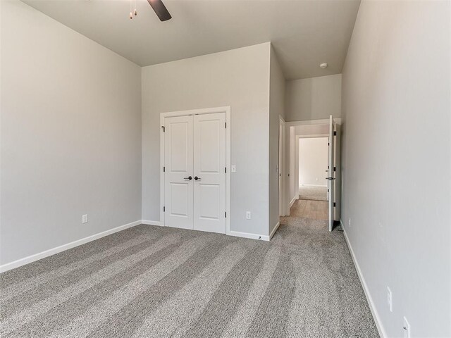 unfurnished bedroom with ceiling fan, light carpet, and a closet