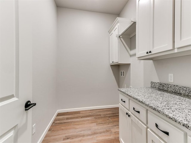 laundry room featuring washer hookup, cabinets, and light hardwood / wood-style flooring