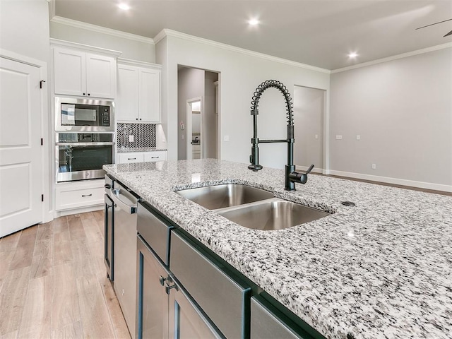 kitchen with white cabinets, sink, light wood-type flooring, appliances with stainless steel finishes, and light stone counters