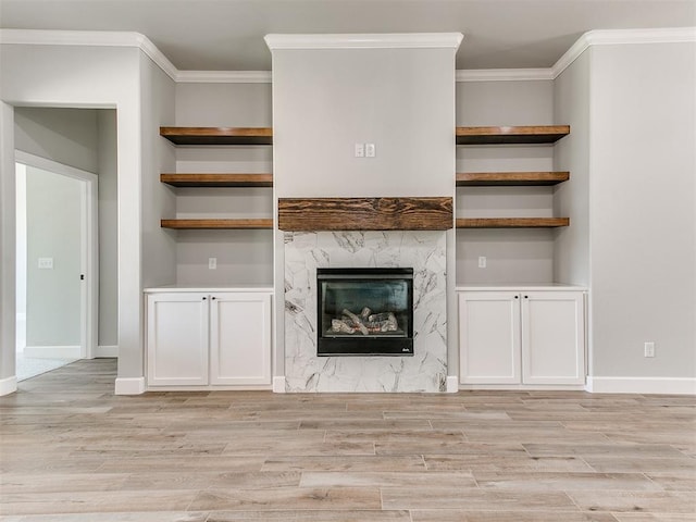 unfurnished living room featuring light wood-type flooring, a premium fireplace, and crown molding