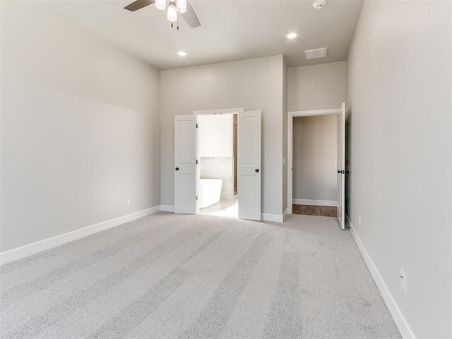 unfurnished bedroom featuring light carpet, connected bathroom, and ceiling fan