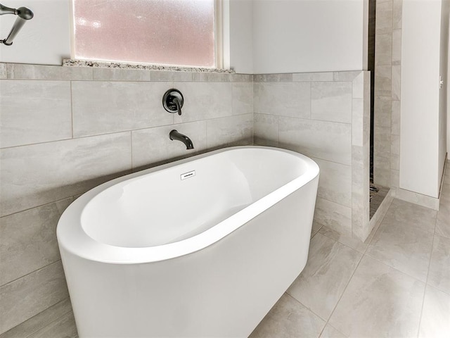 bathroom featuring tile patterned floors, a bathtub, and tile walls