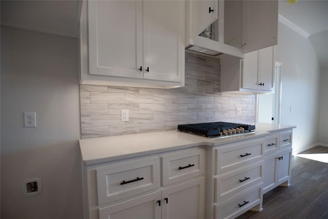 kitchen with backsplash, crown molding, dark hardwood / wood-style floors, white cabinetry, and stainless steel gas cooktop