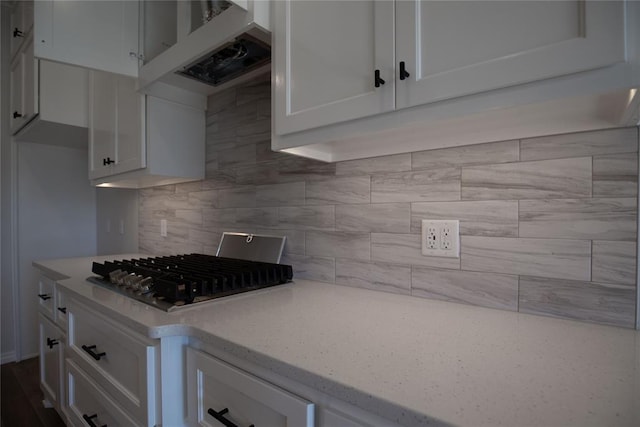 kitchen with white cabinetry, tasteful backsplash, light stone counters, extractor fan, and stainless steel gas stovetop