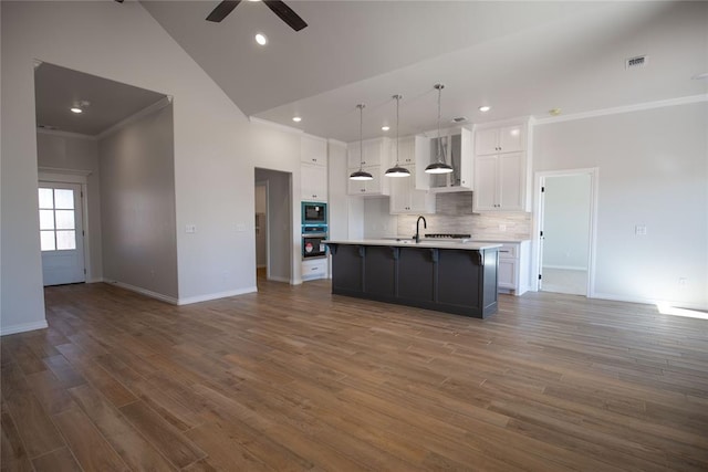 kitchen with dark hardwood / wood-style flooring, white cabinetry, a center island with sink, and high vaulted ceiling