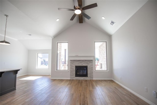 unfurnished living room featuring a fireplace, ceiling fan, plenty of natural light, and light hardwood / wood-style flooring